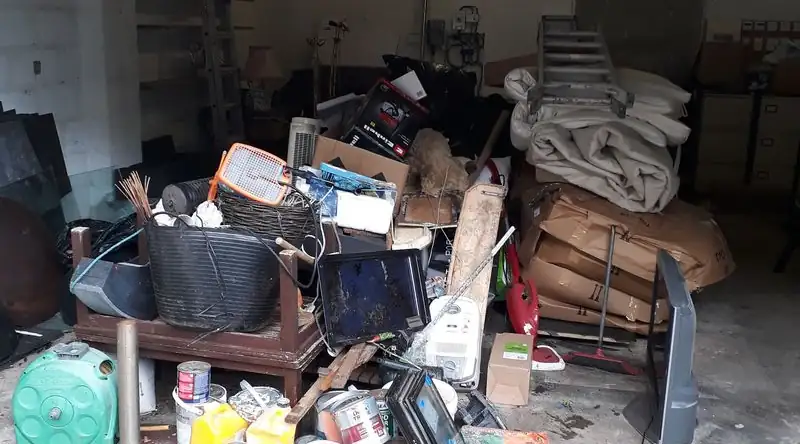 Garage full of household items, tools and paint tins awaiting clearance