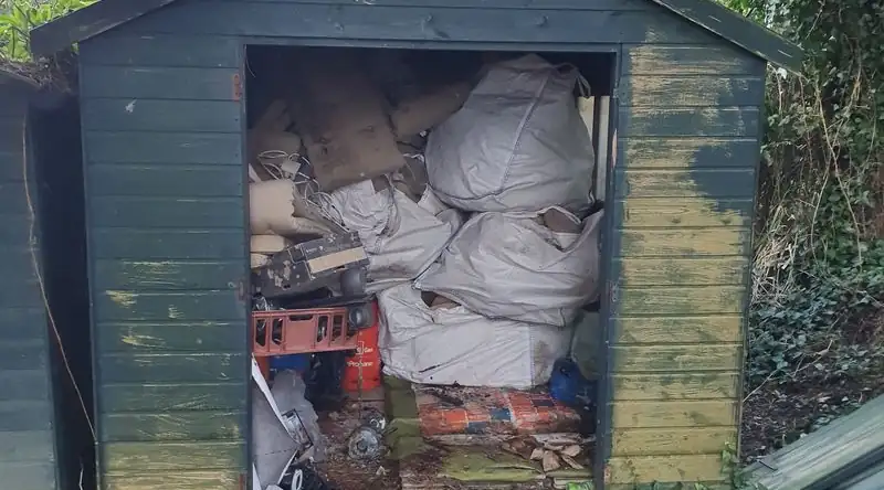 Garden shed packed with bags and boxes ready to be cleared