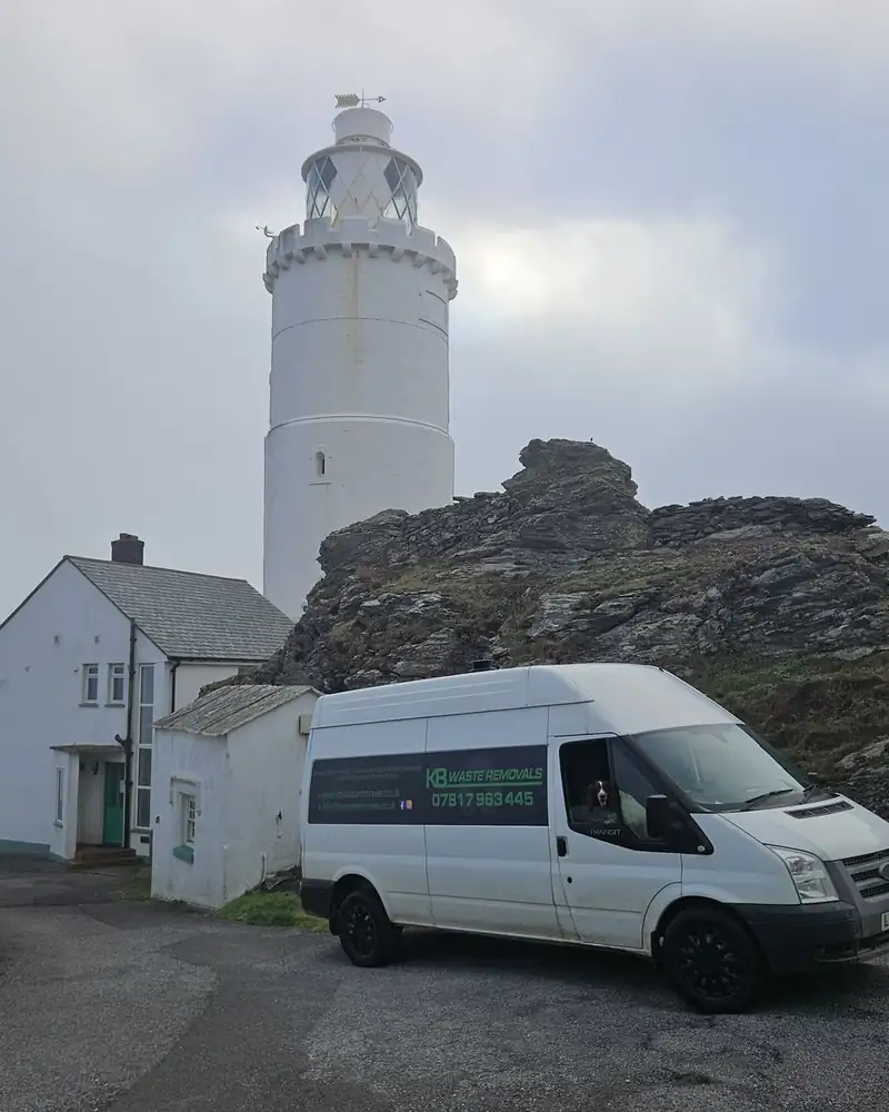 KB Waste Removals van parked below a white lighthouse on a rocky headland